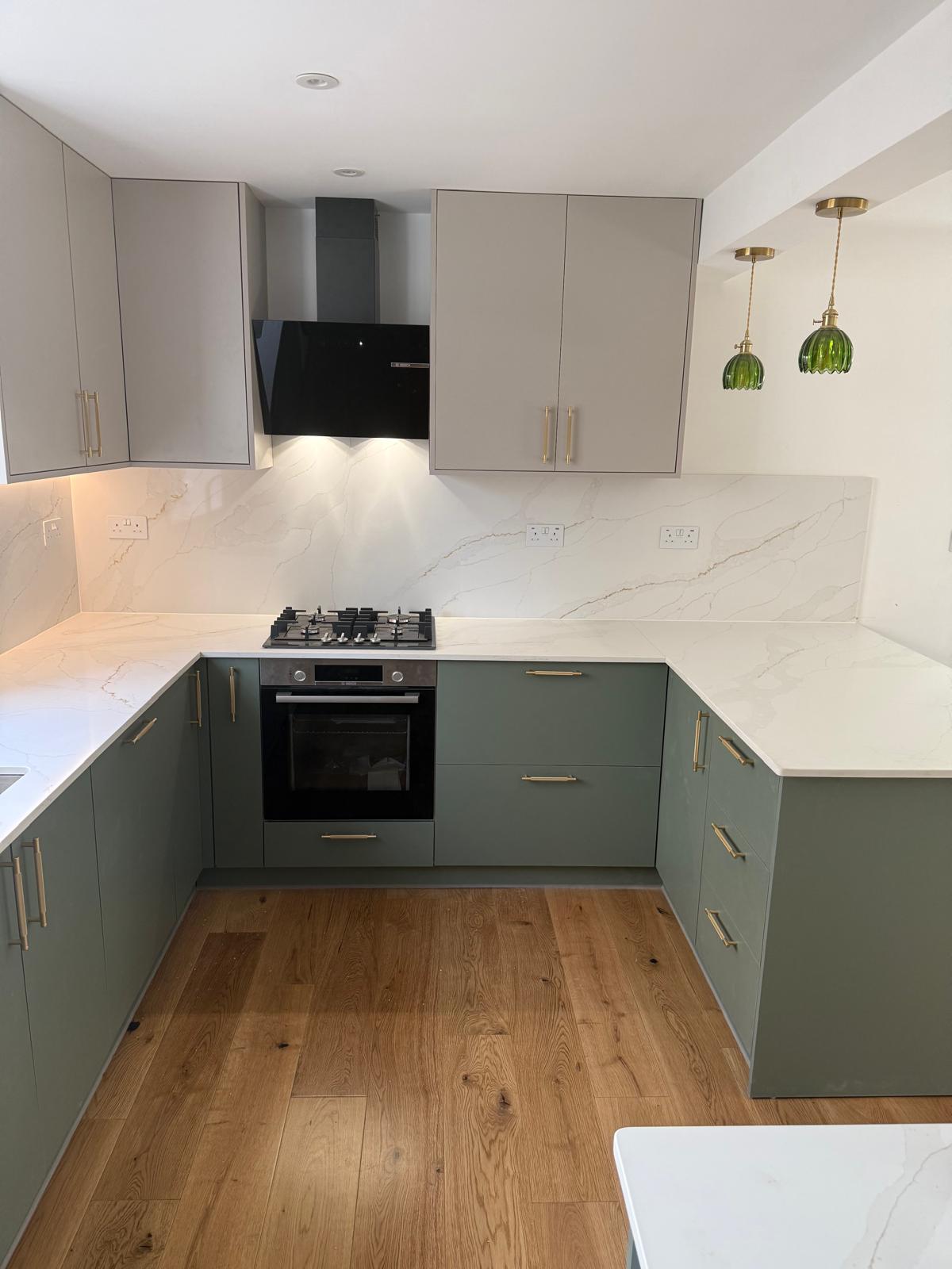Kitchen cabinetry with brass handles and green pendant lights