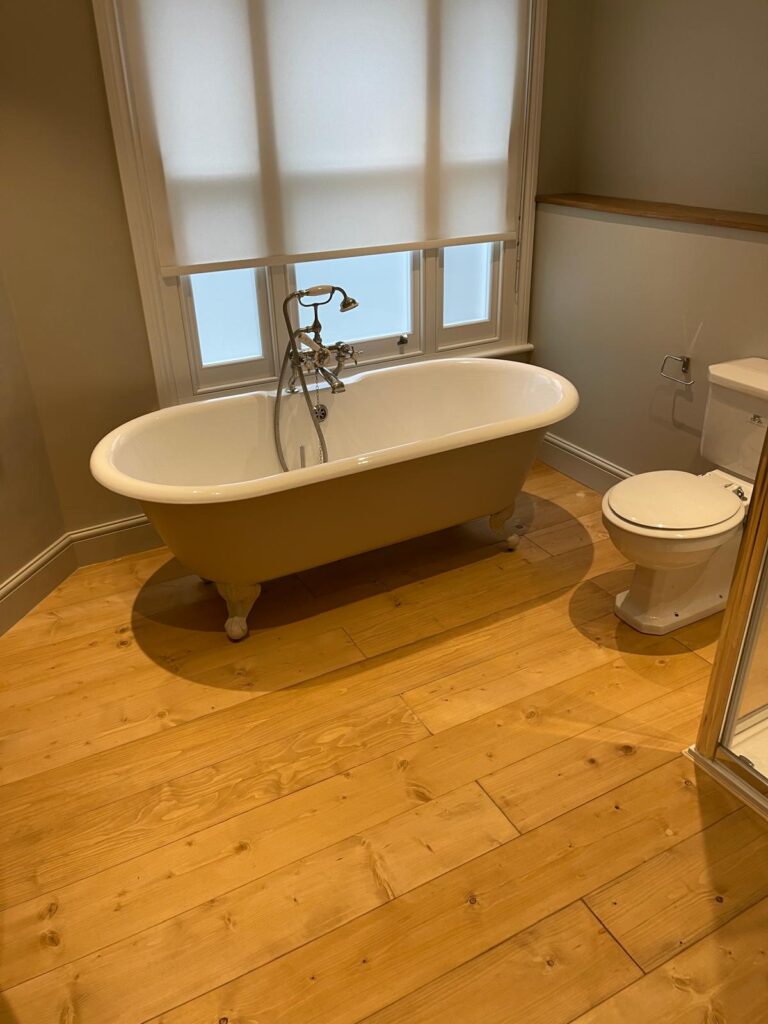 Wood flooring fitted in a period bathroom with roll-top bath, West London