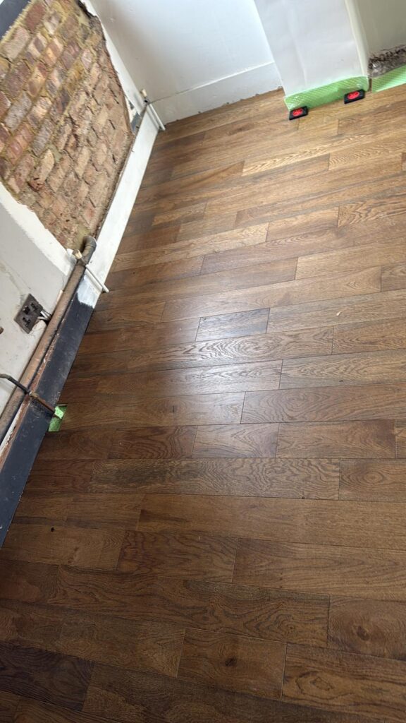 Dark oak floorboards being laid during a period property renovation, West London